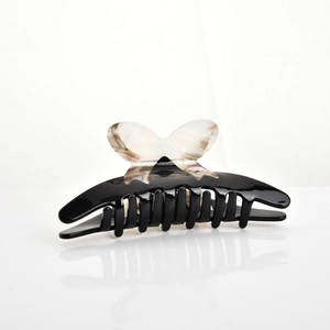 Detailed close-up of a large black hair claw clip with a marble butterfly design