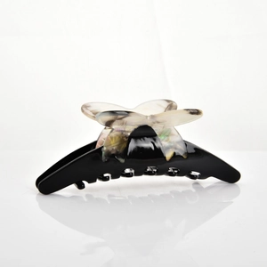 Detail of large black resin hair claw clip with pearlescent marble butterfly accent
