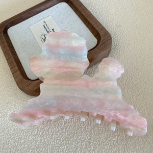 Dettaglio della grande molletta per capelli effetto marmo pastello su vassoio in legno