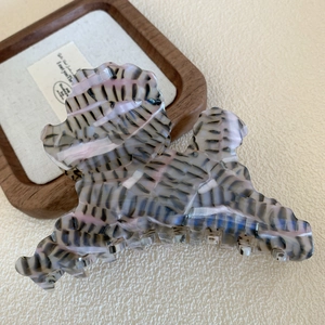 Dettaglio di un mollettone per capelli a forma di barboncino in acetato grigio-rosa