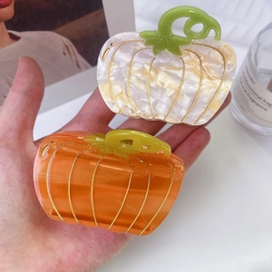 Detailed view of pumpkin-shaped acetate hair claws in pearl white and crystal orange colors