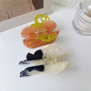 Detail of pumpkin-shaped hair claw and butterfly clip with pearlescent acetate finish