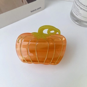 Macro detail of pumpkin hair claw clip with gold silk outlines on acetate orange finish