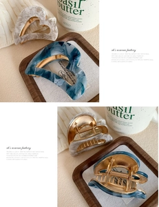 Detail of heart-shaped marble acetate hair claws with gold metal springs and marble texture
