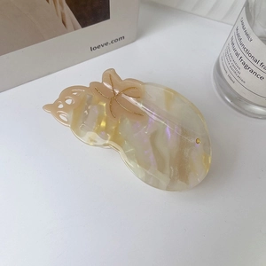 Detailed view of the marbled acetate hair claw clip with golden glitter accents on a desk