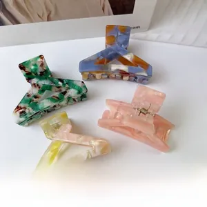 Close-up of four large acetate triangle hair claws with colorful marble patterns