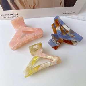 Three acetate triangle hair claws with elegant marble texture on a white background