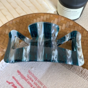 Grande pince à cheveux en acétate marbré bleu sarcelle sur un plateau tressé