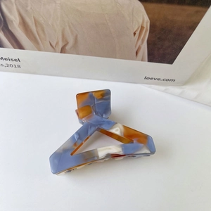 Close-up of triangle acetate hair claw clip with blue and orange marble texture design