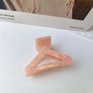 Detailed view of pink marble acetate triangle hair claw clip on a minimalist background