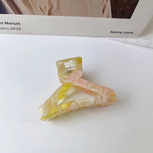 Detail of triangular acetate hair claw clip with pink and yellow marble texture