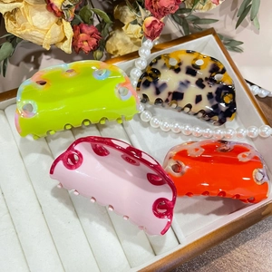 Close-up of acetic acid hair claws in colorful wave designs on white velvet tray