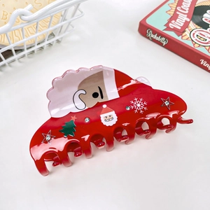 Close-up of red Christmas hair claw with Santa Claus, rhinestone stars and snowflakes