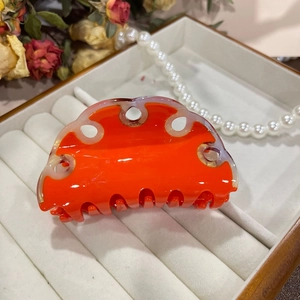 Detailed view of an orange marble acetate hair claw clip with cutout design on jewelry box