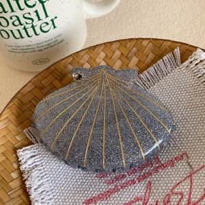Détail de la pince à cheveux en forme de coquillage, résine grise brillante et lignes d'or