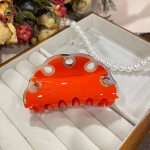 Detailed view of glossy orange cellulose acetate wave hair claw clip in a gift box