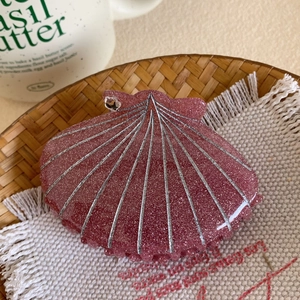 Détail d'une pince à cheveux coquillage rose avec lignes argentées et paillettes fines