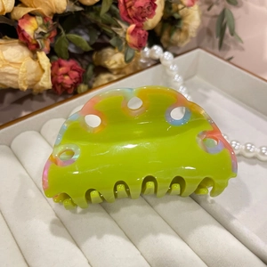 Detailed close-up of wavy neon green acetate hair claw with colorful marble patterns