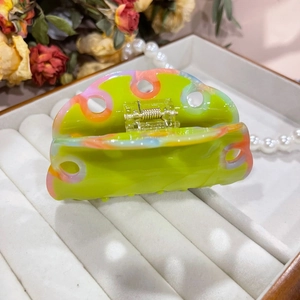 Macro detail of wave hair claw in fruit green with colorful marbled texture and cutout design