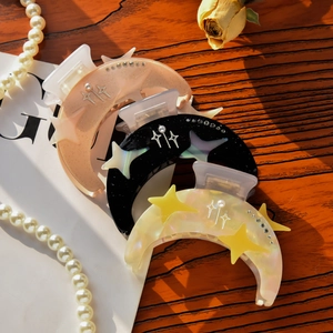 Star and moon crescent hair clips with pearls and rhinestones on a wooden background