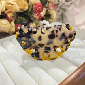 Detail of tortoiseshell acetate claw clip with wave design on a luxury jewelry tray