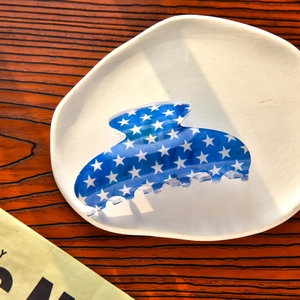 Détail d'une grande pince à cheveux bleue à étoiles blanches sur assiette céramique