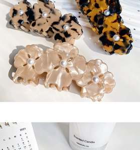 Détail de pinces à cheveux en acétate à fleurs avec perles en léopard et crème