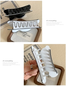 Detail view of large wavy acetate claw clips in black and white colors for thick hair styling