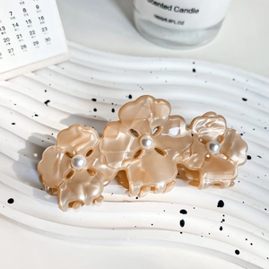 Détail d'une pince à cheveux trèfle en acétate avec perles en rose poudré élégant
