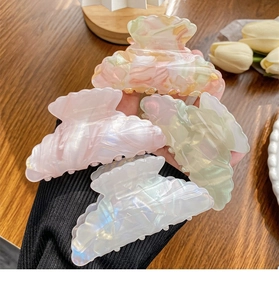 Close-up of four colorful acetic hair claws held in hand against a wooden background
