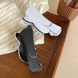 Cute bird-shaped acetate hair claws in black and white on a cozy wooden tray