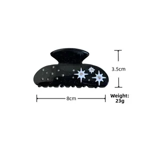 Detailed view of black acetate hair claw clip with star patterns and sparkling rhinestones