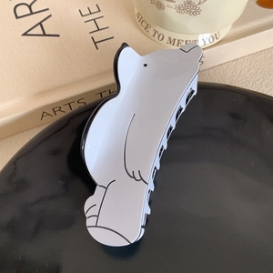 Detailed view of a white polar bear acetate hair claw clip on a decorative tray