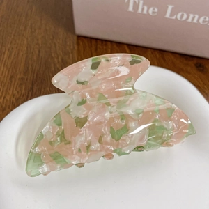 Macro shot of large acetate hair claw clip with pink and green floral stone texture