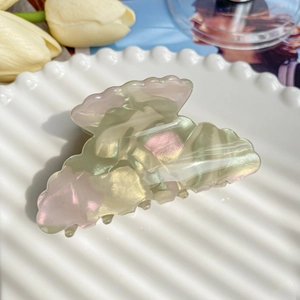 Close-up of marble pattern hair claw clip with pastel green and pink shell-like texture