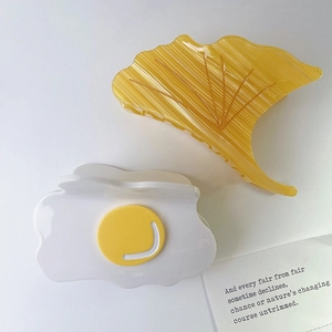 Detailed close-up of acetate ginkgo leaf and egg hair claw clips on white background