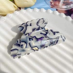 Detail of large white and purple marble acetate hair claw clip on a ceramic tray