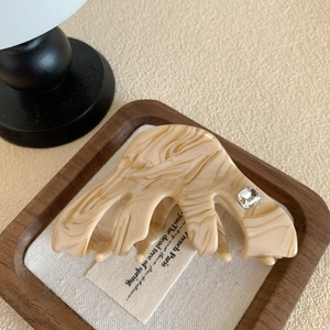 Détail d'une pince à cheveux motif marbre avec cristal carré sur surface en lin