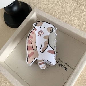 Détail d'une mignonne pince à cheveux chat blanc avec nœud rouge sur une surface beige