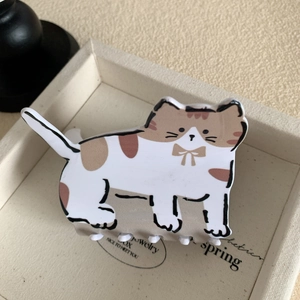 Détail d'une pince à cheveux motif chat calicot avec nœud sur un plateau à bijoux