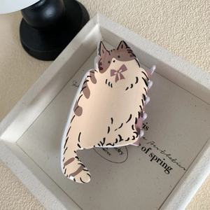 Gros plan d'une pince à cheveux chat beige avec nœud et détails de motifs tigrés