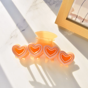 Detail einer warm-orangen Haarklammer aus Acetat mit vier süßen Herzmustern verziert
