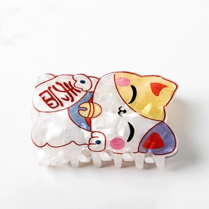 Détail de la pince à cheveux chat porte-bonheur en blanc nacré avec motif pièce