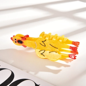 Vue détaillée de la pince à cheveux poulet jaune avec strass et texture marbrée