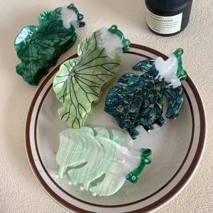 Leaf-shaped acetate hair claws with marble green patterns and rhinestone accents