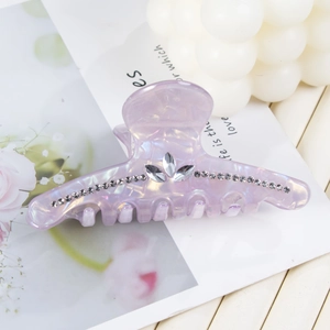 Détail d'une pince à cheveux violette nacrée ornée d'élégants strass en forme de feuilles
