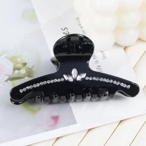 Détail d'une pince à cheveux noire brillante ornée de motifs floraux en strass étincelants