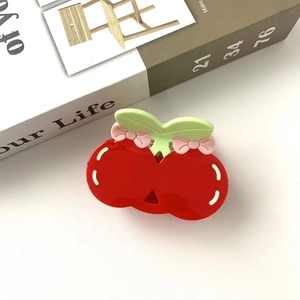 Detail view of cute red cherry hair claw clip with green leaves and pink bow decoration