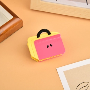 Detail view of a pink and yellow briefcase-shaped hair claw clip made of acetate