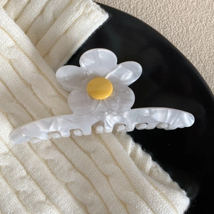Détail macro d'une pince à cheveux en fleur d'acétate blanc avec un centre jaune vif